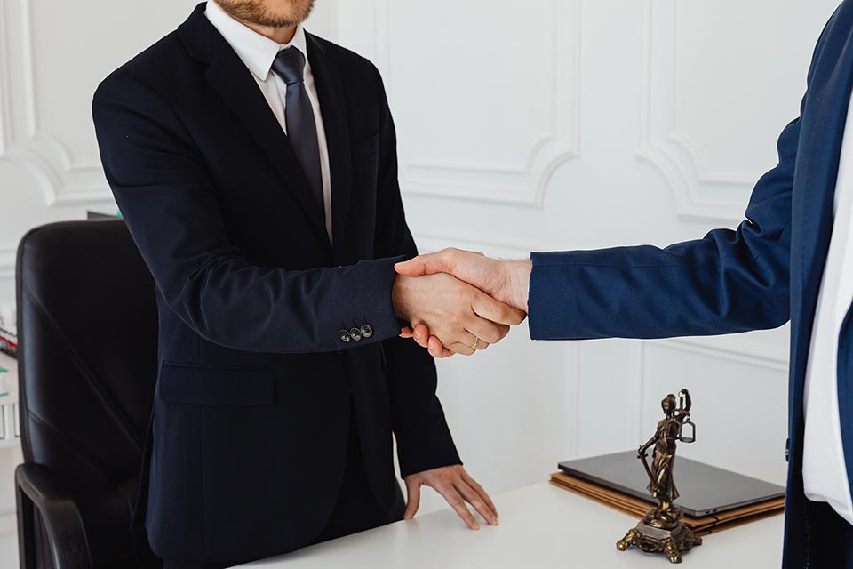Lawyers shaking hands in an office setting, symbolizing legal representation and partnership related to DUI checkpoint enforcement in Texas.