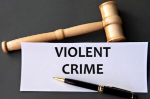 VIOLENT CRIME - words on white paper on dark background with judge's gavel.