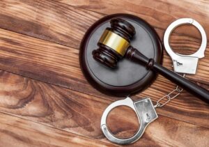 Gavel with stand and handcuffs on the wooden background.
