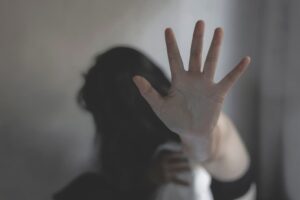 A person holds up their hand in a stop gesture, suggesting fear, refusal, or self-protection.