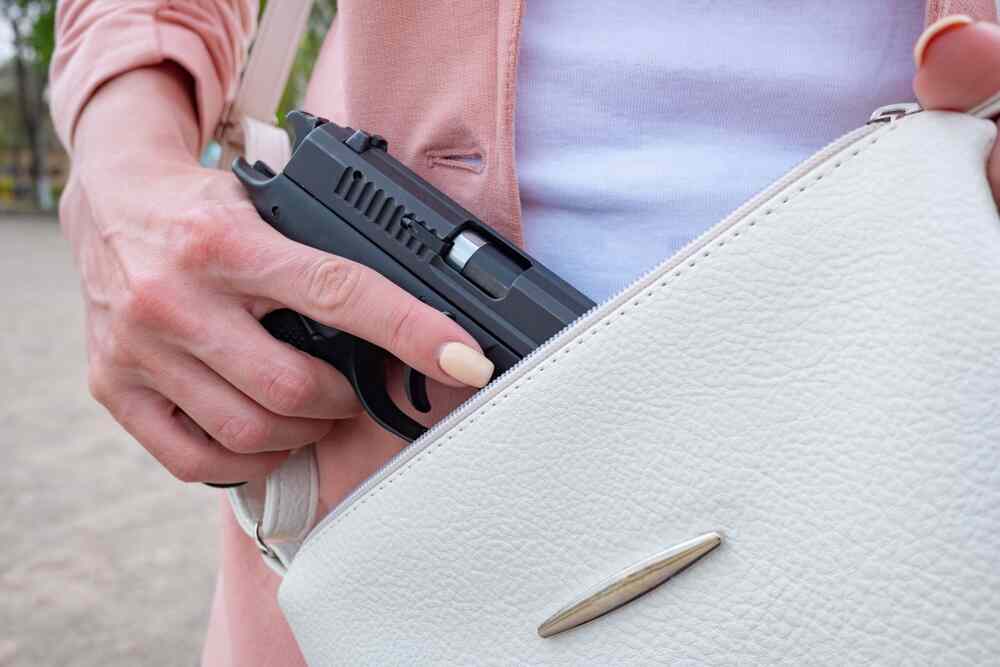 Woman with concealed weapon gun in her white small handbag.