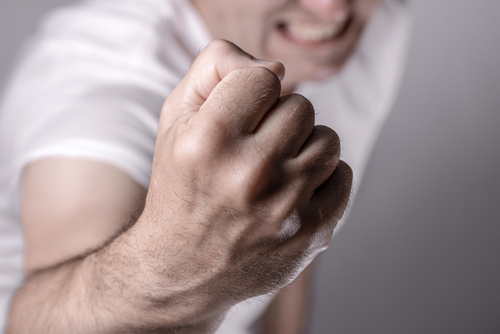 A man with a raised fist in an aggressive pose, representing violent crime charges handled by a Houston criminal lawyer.